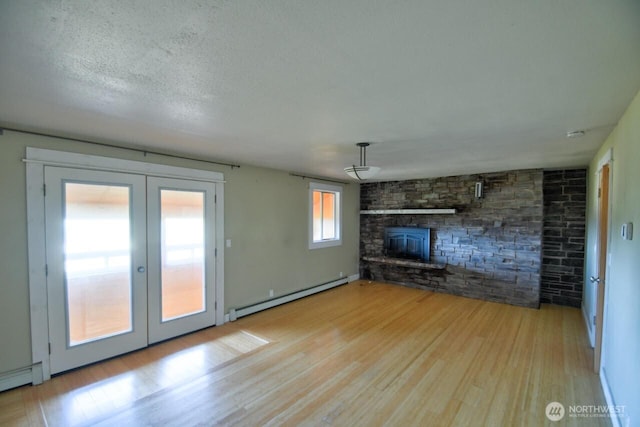 unfurnished living room with a baseboard radiator, a fireplace, wood finished floors, and french doors