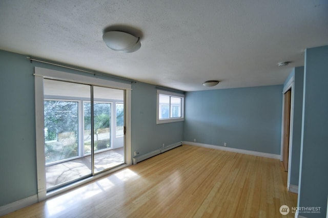 spare room with a textured ceiling, light wood-type flooring, a baseboard radiator, and baseboards