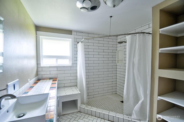 full bath with a tile shower and a sink