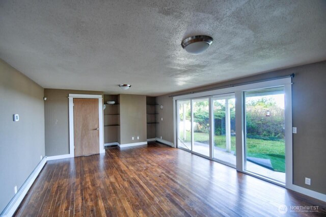 empty room featuring a textured ceiling, baseboards, and wood finished floors