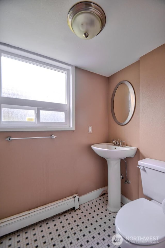 bathroom with a baseboard radiator, baseboards, and toilet