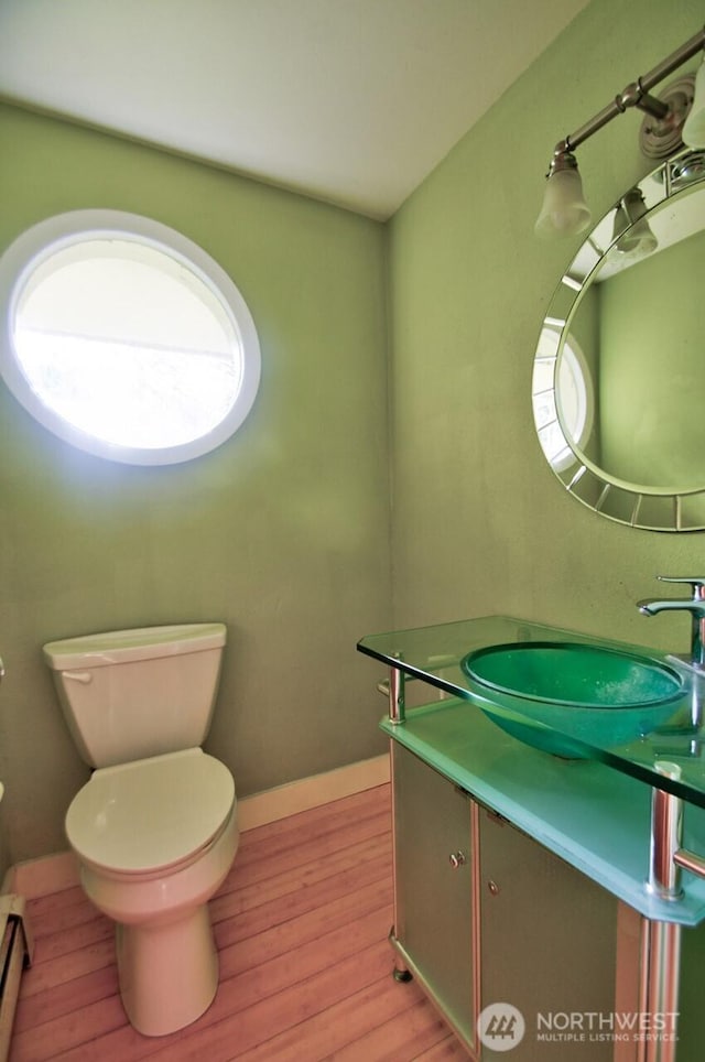 bathroom with baseboards, vanity, toilet, and wood finished floors