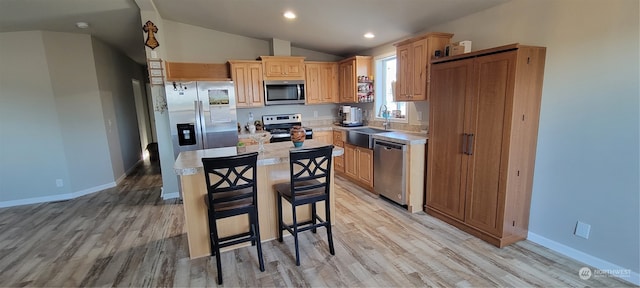 kitchen featuring vaulted ceiling, light hardwood / wood-style flooring, stainless steel appliances, and sink