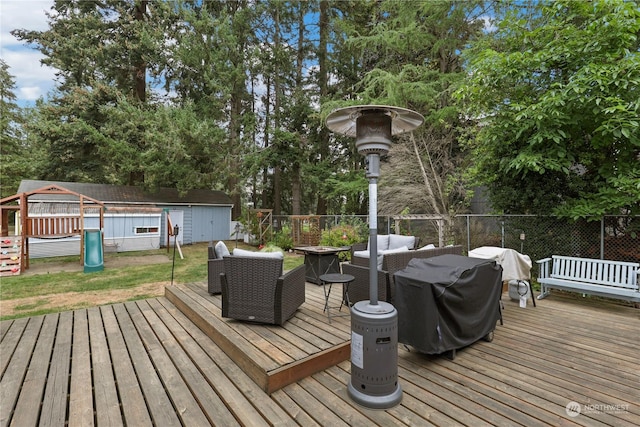 deck with an outbuilding, a playground, a storage unit, and fence