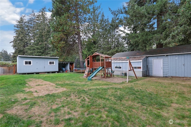 view of yard featuring a storage unit, an outbuilding, a trampoline, and fence