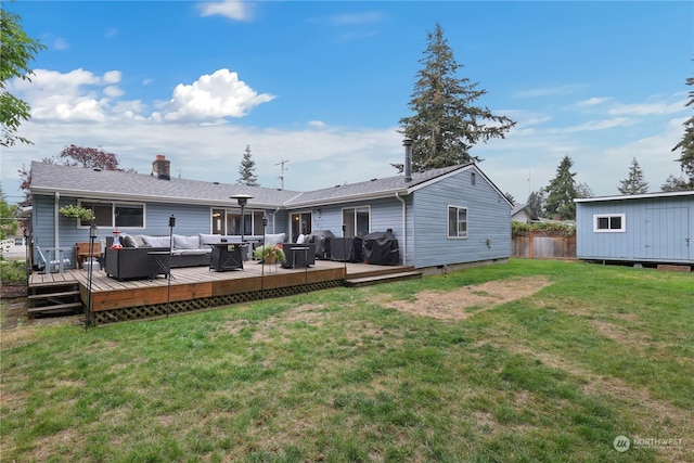 back of house featuring an outbuilding, fence, a wooden deck, a lawn, and an outdoor hangout area