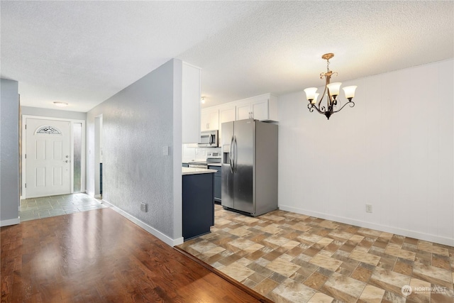 kitchen featuring a textured ceiling, appliances with stainless steel finishes, a chandelier, and light countertops