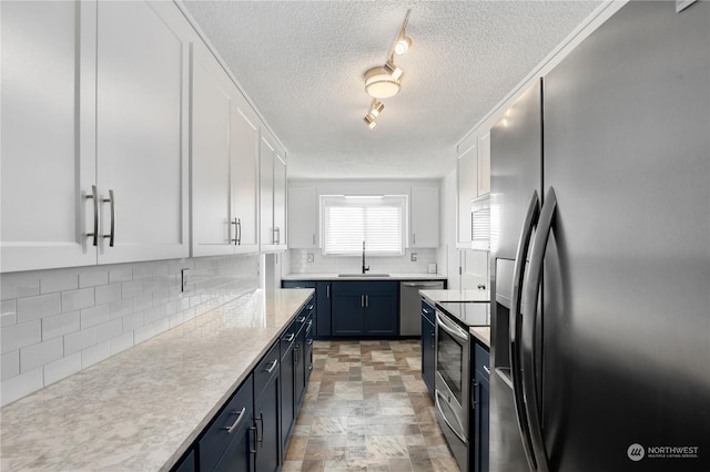 kitchen with light countertops, decorative backsplash, white cabinets, stainless steel appliances, and a sink