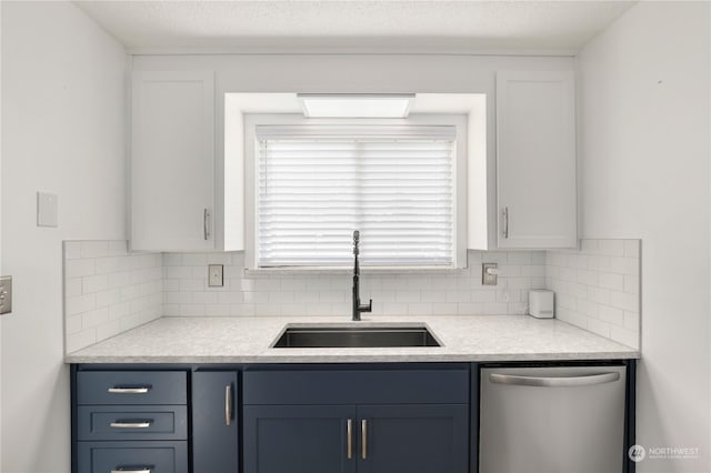 kitchen with stainless steel dishwasher, white cabinetry, backsplash, and a sink