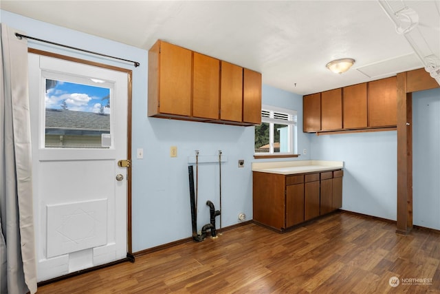 kitchen with brown cabinets, light countertops, dark wood-type flooring, and baseboards