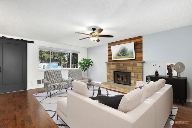 living area with wood finished floors, a fireplace, ceiling fan, a textured ceiling, and a barn door