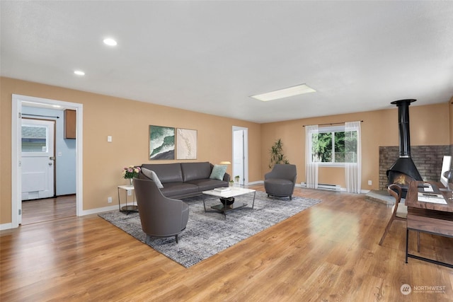 living area featuring baseboards, baseboard heating, recessed lighting, a wood stove, and wood finished floors