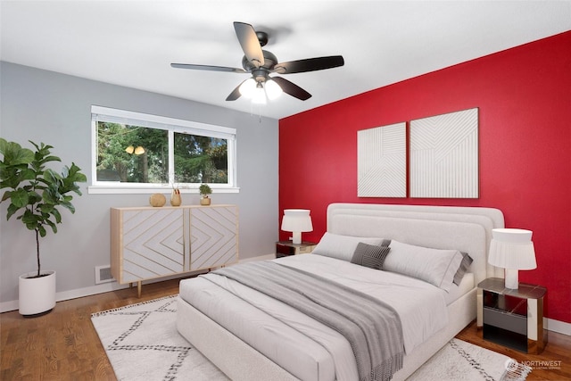 bedroom featuring visible vents, ceiling fan, baseboards, and wood finished floors