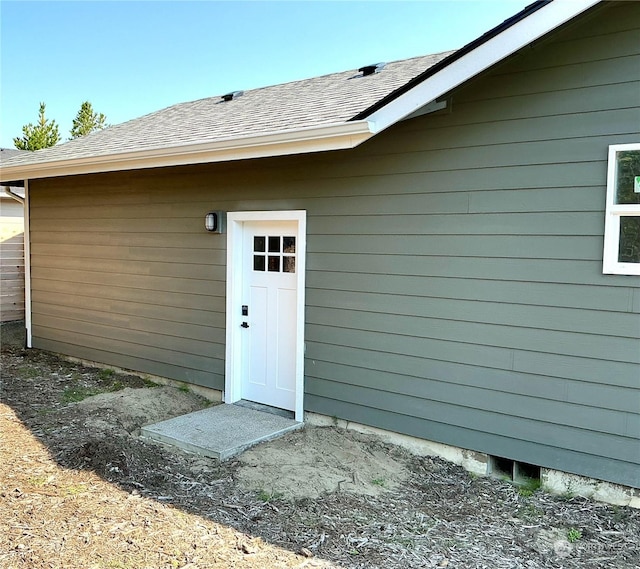 doorway to property featuring roof with shingles