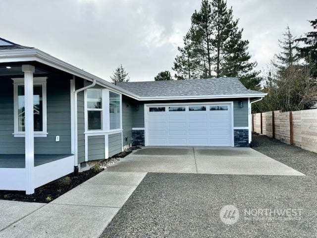 garage featuring concrete driveway and fence