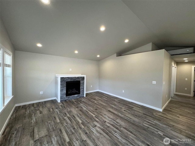 unfurnished living room featuring a stone fireplace, baseboards, lofted ceiling, and dark wood-style flooring