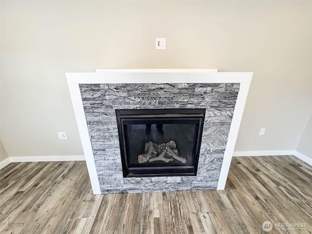 interior details with a fireplace, baseboards, and wood finished floors