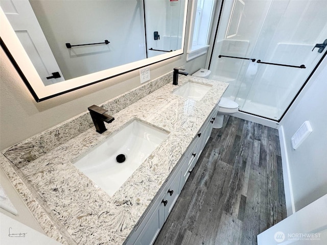 full bathroom featuring double vanity, toilet, wood finished floors, and a sink