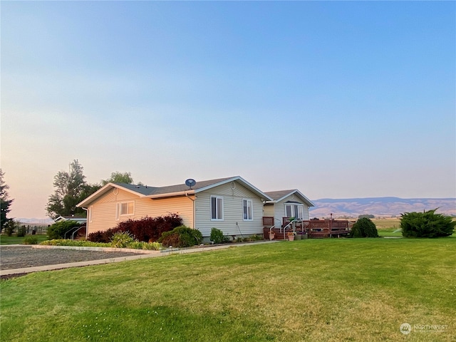 single story home with a mountain view and a lawn