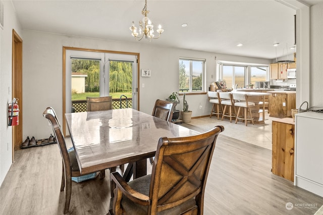 dining area featuring light wood-type flooring and an inviting chandelier