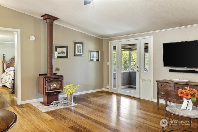 entryway with vaulted ceiling, ornamental molding, wood-type flooring, and a wood stove