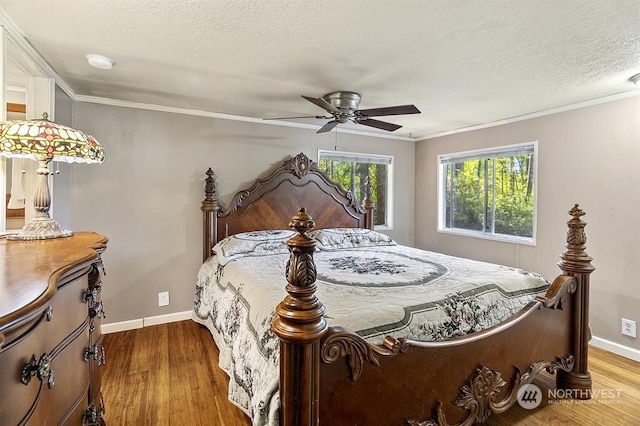 bedroom with a textured ceiling, ornamental molding, wood finished floors, and baseboards