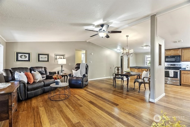 living area with light wood-style floors, lofted ceiling, visible vents, and a textured ceiling