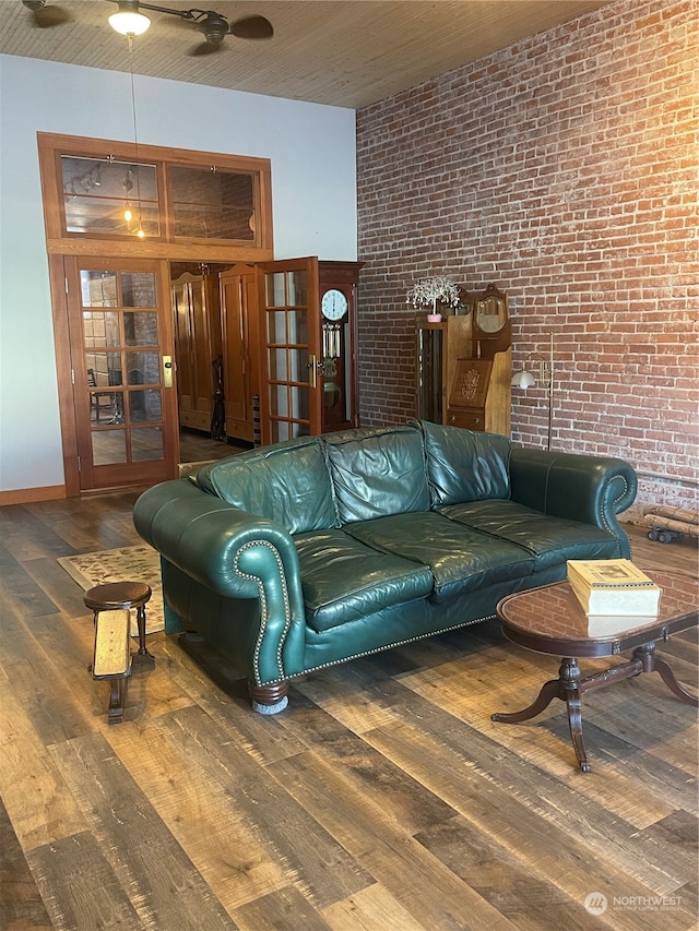 living room with ceiling fan, wood-type flooring, and brick wall