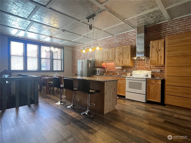 kitchen with hanging light fixtures, stainless steel appliances, brick wall, dark hardwood / wood-style floors, and a breakfast bar area