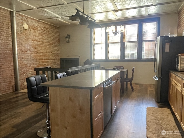 kitchen with a center island, an inviting chandelier, brick wall, dark hardwood / wood-style floors, and a breakfast bar area