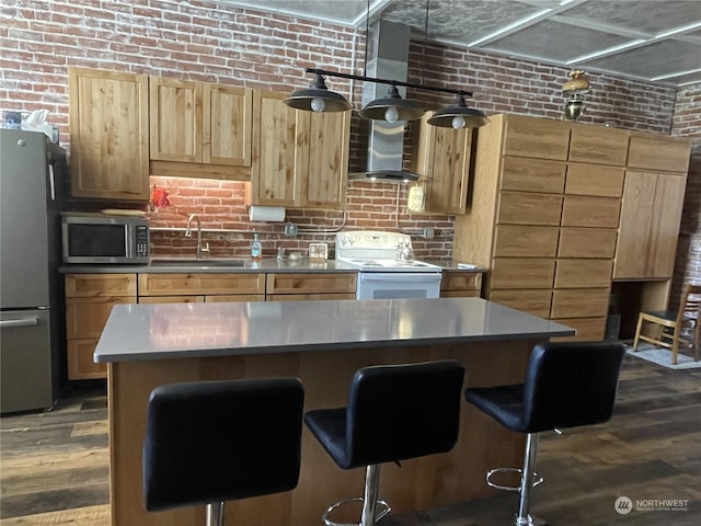 kitchen featuring stainless steel appliances, dark hardwood / wood-style flooring, sink, wall chimney exhaust hood, and brick wall