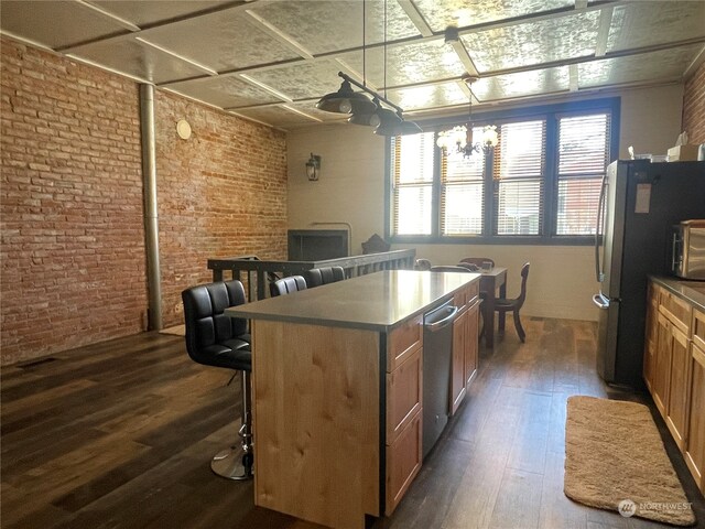 kitchen with brick wall, dark hardwood / wood-style flooring, a kitchen bar, and a center island