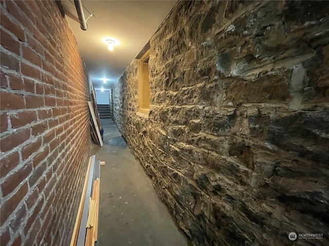 hall with concrete floors and brick wall