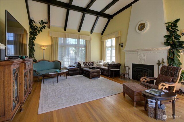 living room with light hardwood / wood-style floors, vaulted ceiling with beams, and a tile fireplace