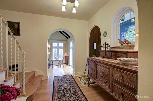 entrance foyer with vaulted ceiling, a notable chandelier, and light wood-type flooring