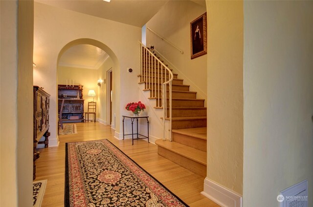 foyer with ornamental molding and light hardwood / wood-style floors