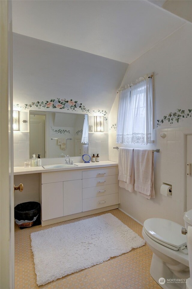 bathroom with vanity, toilet, tile patterned flooring, and lofted ceiling