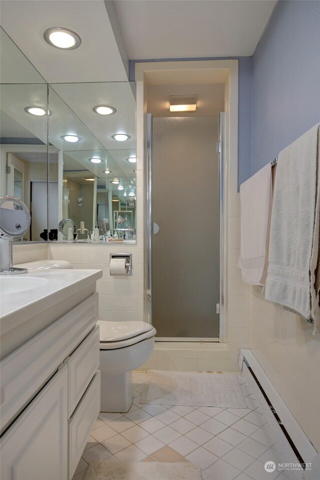 bathroom with a shower with door, vanity, a baseboard radiator, toilet, and tile patterned floors