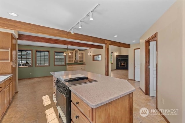 kitchen featuring stainless steel electric range, a fireplace, beamed ceiling, track lighting, and a kitchen island