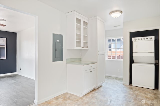 kitchen featuring white cabinetry, electric panel, ceiling fan, and stacked washing maching and dryer