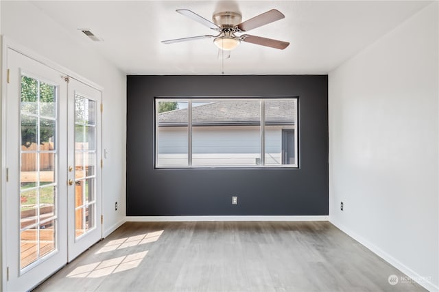 empty room featuring a healthy amount of sunlight, ceiling fan, light hardwood / wood-style flooring, and french doors