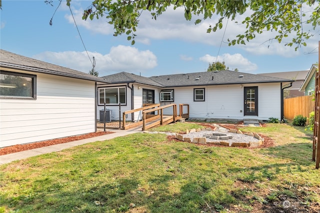 rear view of house featuring a fire pit, central air condition unit, and a lawn