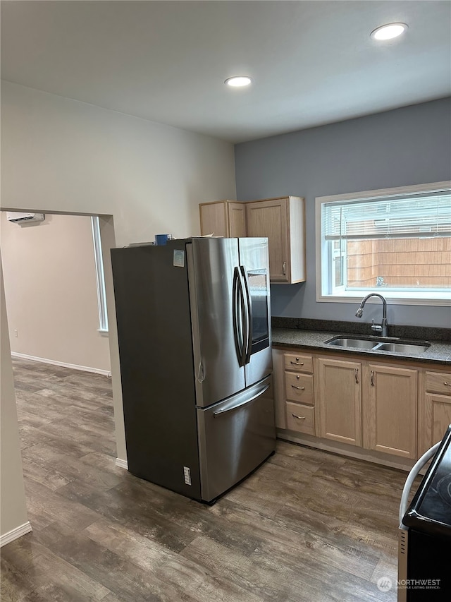 kitchen with light brown cabinetry, dark wood-type flooring, stainless steel fridge, and sink