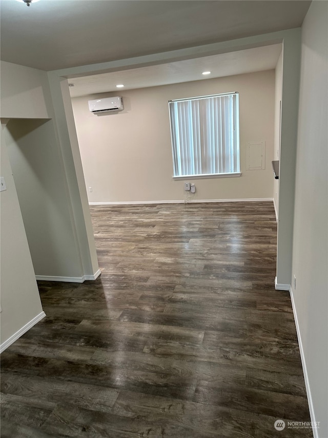 empty room with a wall unit AC and dark hardwood / wood-style floors