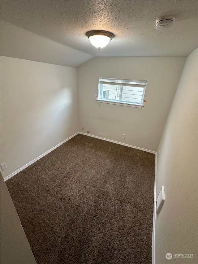 carpeted empty room with a textured ceiling and vaulted ceiling