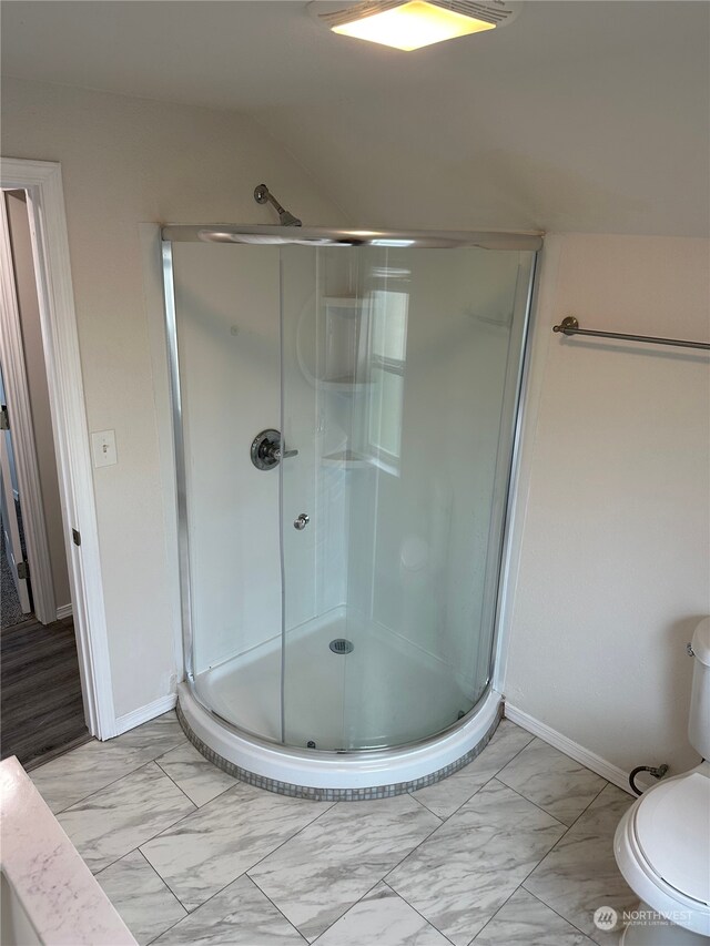 bathroom featuring vaulted ceiling, toilet, and a shower with door