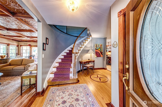 foyer entrance featuring coffered ceiling, light hardwood / wood-style floors, and beam ceiling