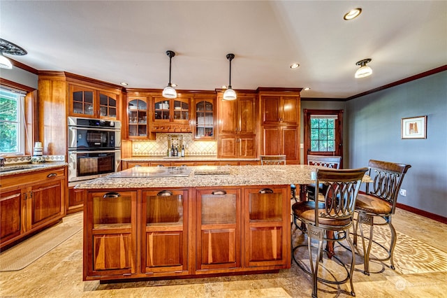 kitchen featuring hanging light fixtures, tasteful backsplash, a kitchen island, light stone countertops, and double oven