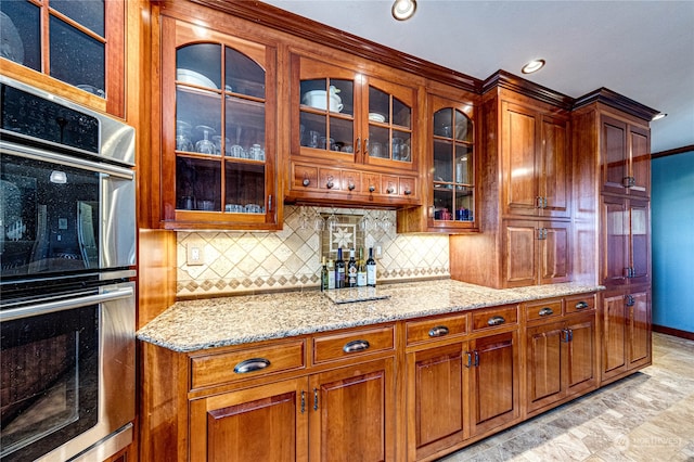 kitchen with double oven, light stone counters, and tasteful backsplash