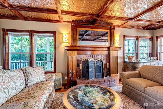 living room featuring wood-type flooring, coffered ceiling, and a brick fireplace